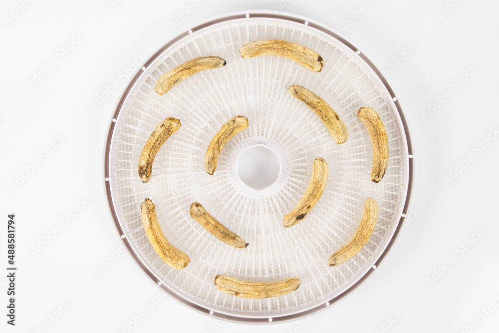 dried mini bananas on drying trays on white background