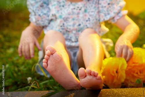 The legs of a little girl on the green grass on a summer or spring day. A sick disabled girl on vacation in nature photo