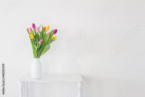 Fototapeta Naklejka Na Ścianę i Meble -  tulips in white vase on wooden shelf on white background