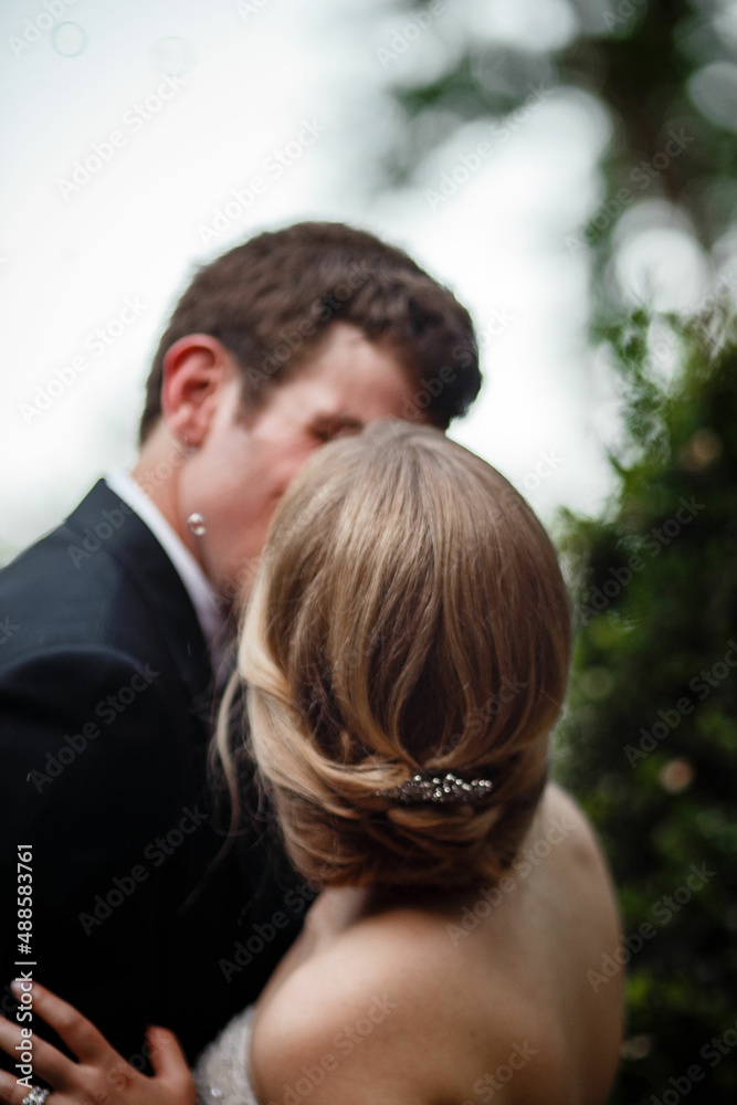 Bride and groom kissing tenderly Close up portrait of a young bride and groom kissing against blue sky Groom in a black suit and bride in a white gown with an open back Bride and groom kissing tenderly Close up portrait of a young bride and groom kissing against blue sky Groom in a black suit and bride in a white gown with an open back