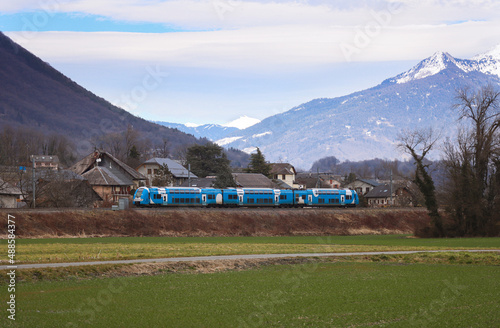 A French regional express train in a countryside of France during winter time, surround with scenic landscape of nature and mountain alps of Rhône-Alpes region in background