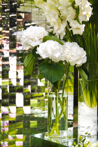 White vase with flowers in a restaurant, served table. Basket with flowers, kibana, wedding floristry. photo