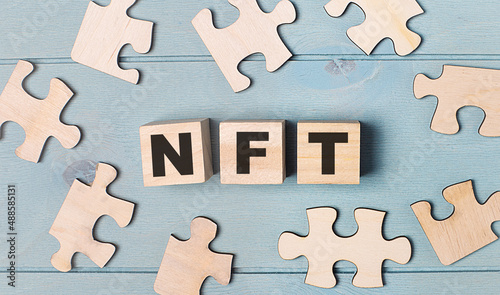 Blank puzzles and wooden cubes with the text NFT Non-Fungible Token lie on a light blue background.