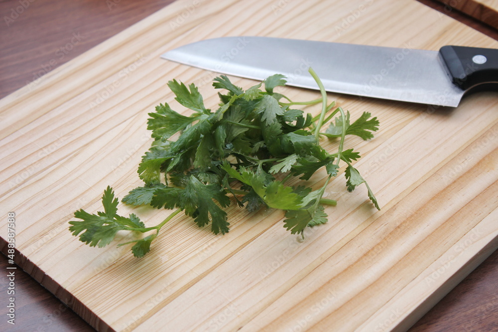chopped cilantro and knife Place it on a wooden cutting board inside a wooden table. chopped cilantro and knife Place it on a wooden cutting board inside a wooden table.