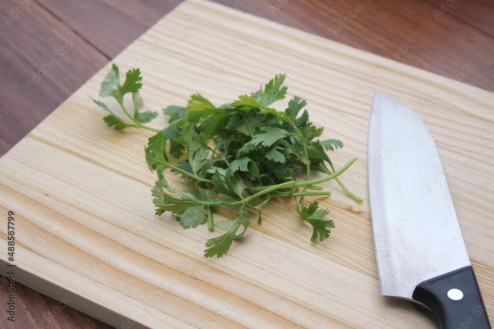 chopped cilantro and knife Place it on a wooden cutting board inside a wooden table. chopped cilantro and knife Place it on a wooden cutting board inside a wooden table.