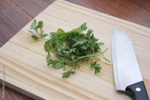 chopped cilantro and knife Place it on a wooden cutting board inside a wooden table.
