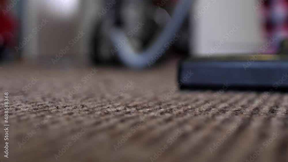Close-up of a vacuum cleaner brush while cleaning. A woman or a man vacuums carpet. Macro shot of the texture of the carpet on which the vacuum cleaner removes dust and dirt. Close-up of a vacuum cleaner brush while cleaning. A woman or a man vacuums carpet. Macro shot of the texture of the carpet on which the vacuum cleaner removes dust and dirt.