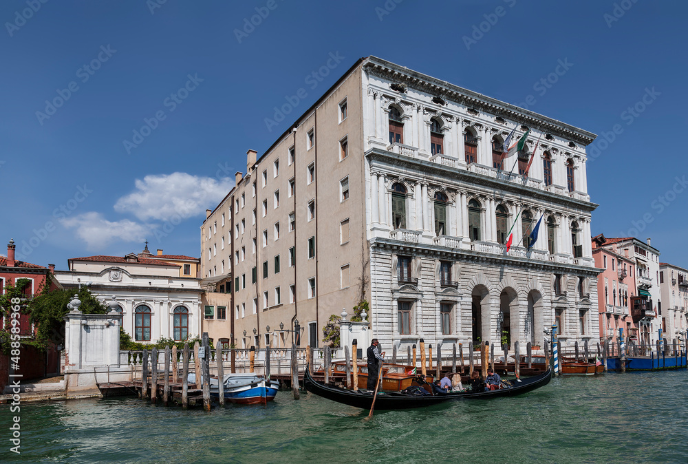 Palazzo Corner della Ca'Grande on the banks of the Grand Canal and a gondola with tourists. Venice, Italy