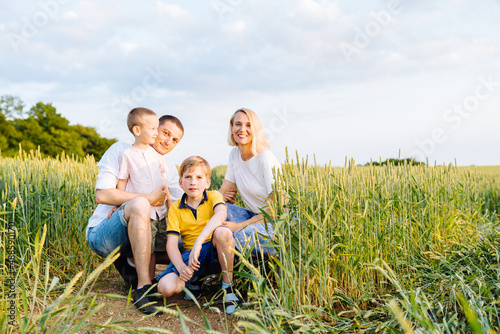 Parents and two sons relationship. Mom and dad hugs their kids. Walking on a beautiful fiels. Children and parents holding hands. Freedom and love concept. Happy family in a nature.