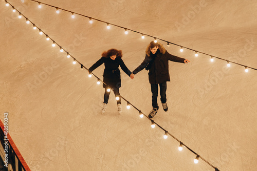 A young couple in love skating, holding hands and smiling, top view