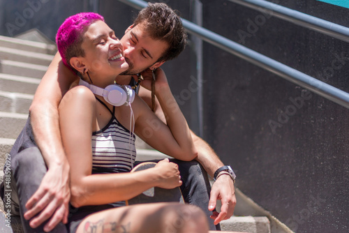 Young couple of skaters in love is sitting on the stairs with their skateboards and enoying of listening to music and being together. Lifestyle concept