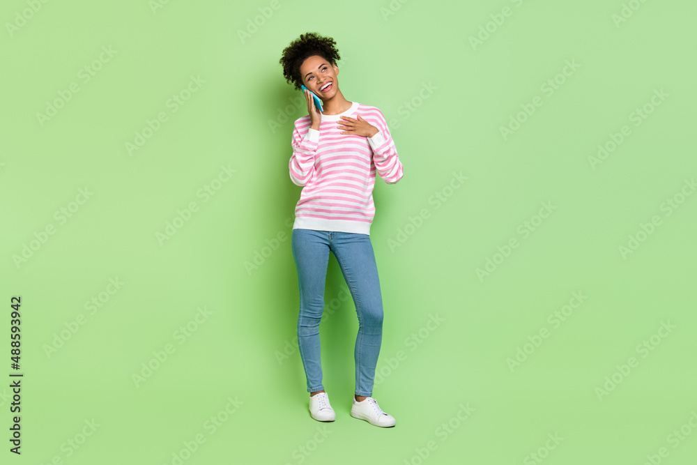 Photo of thoughtful adorable woman wear striped sweater talking modern gadget empty space isolated green color background Photo of thoughtful adorable woman wear striped sweater talking modern gadget empty space isolated green color background