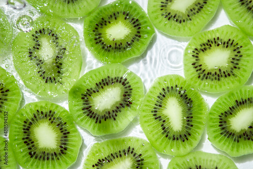 Kiwi slices in water on a white background. Peeled and sliced kiwi.