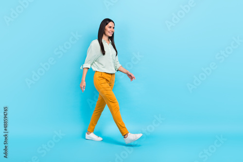 Full body profile side photo of young woman go look empty space wear casual clothes isolated over blue color background photo