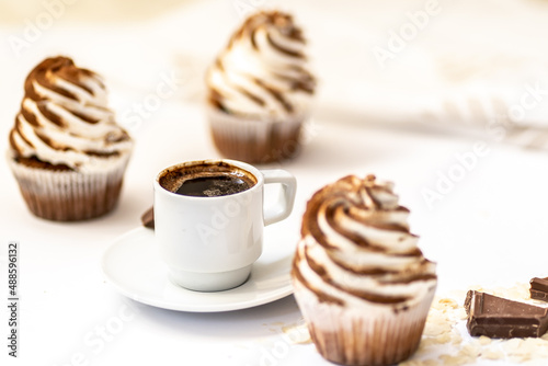 Black coffee with cupcakes and muffins. Spice cupcakes with creamcheese frosting decorated with a cocoa photo