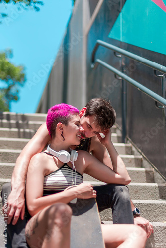 Young couple of skaters in love is sitting on the stairs with their skateboards and enoying of being together. Lifestyle concept