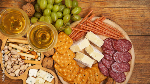 Snack for wine. Cheese and meat plate. Sausage, cheese, nuts, grapes, crackers on wooden table. Italian food for romantic date or meeting with friends