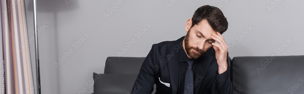 tired businessman in suit sitting on couch in hotel room, banner tired businessman in suit sitting on couch in hotel room, banner