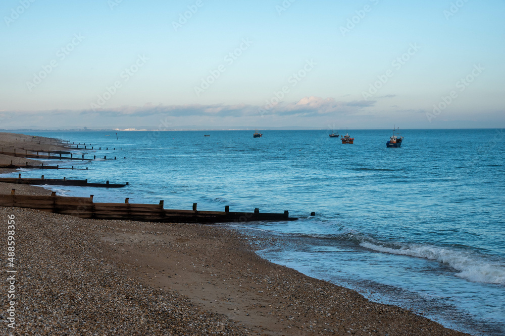 beautiful empty beach in Selsey West Sussex England with fishing boats in the background