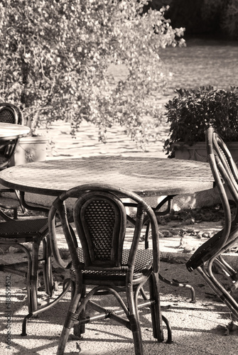 Empty riverside cafe at autumn. France. Round table and wicker chairs. Low season concept. Sepia historic photo. © Elena Dijour