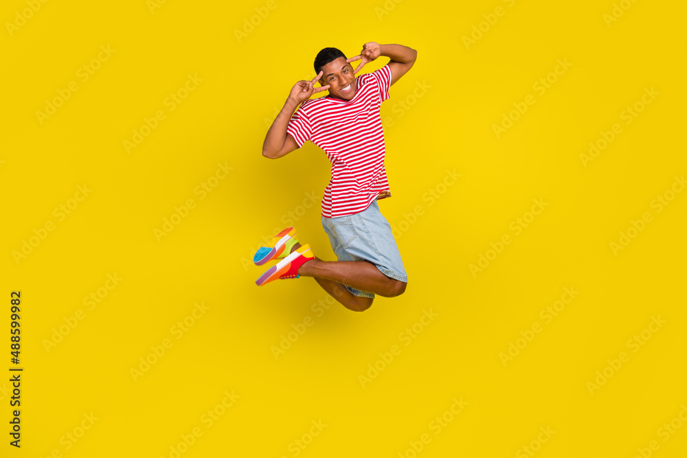 Full body photo of guy jump make v-sign eye wear red striped t-shirt short isolated over bright yellow color background