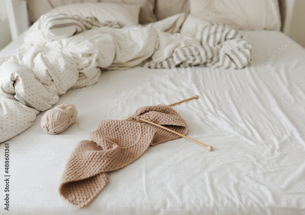 knitting needles and woolen beige yarn in cozy bed at home knitting needles and woolen beige yarn in cozy bed at home