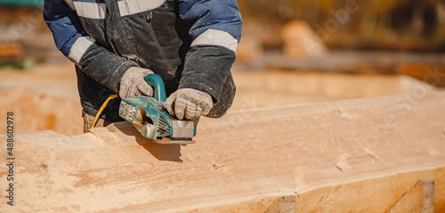Wallpaper Mural Industrial work carpenter grinds log with electric jointer, construction frame building site of house made of wood Torontodigital.ca
