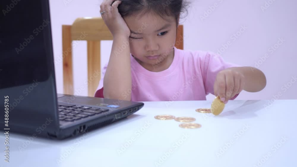 Slow motion scene of a 5-year-old Asian girl collecting bitcoins. fun at the table Slow motion scene of a 5-year-old Asian girl collecting bitcoins. fun at the table