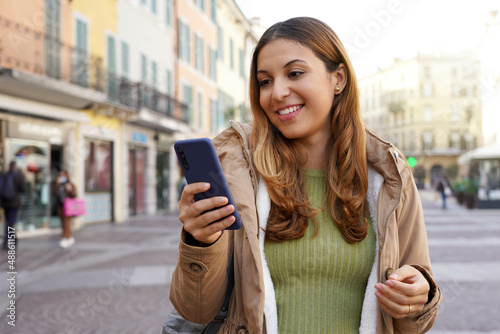 Portrait of girl outdoor messaging with chatting app on smartphone in pedestrian area