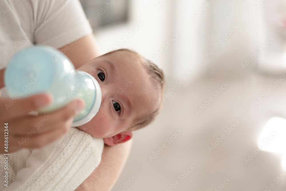 unrecognizable woman feeding the newborn baby with infant milk artificial nutrition. mother's love and warmth unrecognizable woman feeding the newborn baby with infant milk artificial nutrition. mother's love and warmth