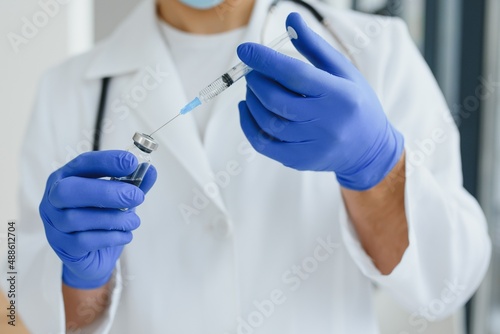 Doctor, scientist, researcher hand in blue gloves holding flu, measles, coronavirus, covid-19 vaccine disease preparing for human clinical trials vaccination shot, medicine and drug concept.