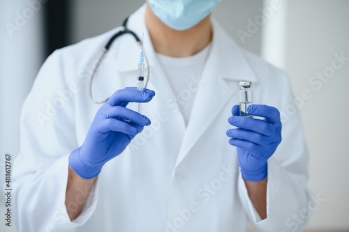 A doctor in blue gloves holding a bottle with vaccine. Close up shot. Medicine and healthcare concept