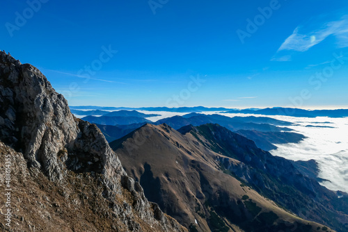 A massive cliff of mount Eisenerzer Reichenstein in Styria, Austria, Europe. Austrian Alps. Bare mountain ridges with view on the cloud covered Ennstal Valley. Hiking trail, Wanderlust. Sunny day