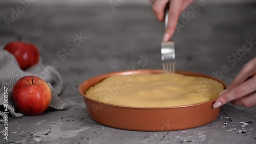 Poking puff pastry with a fork in the process of making apple Tarte Tatin or pie.