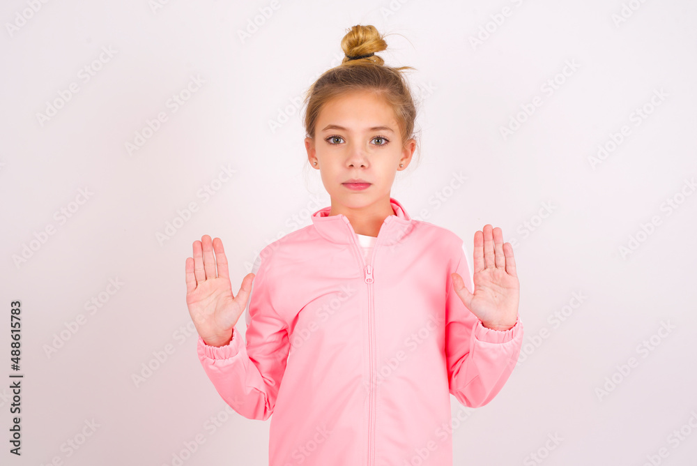 Serious caucasian little kid girl with bun hairstyle wearing pink ...