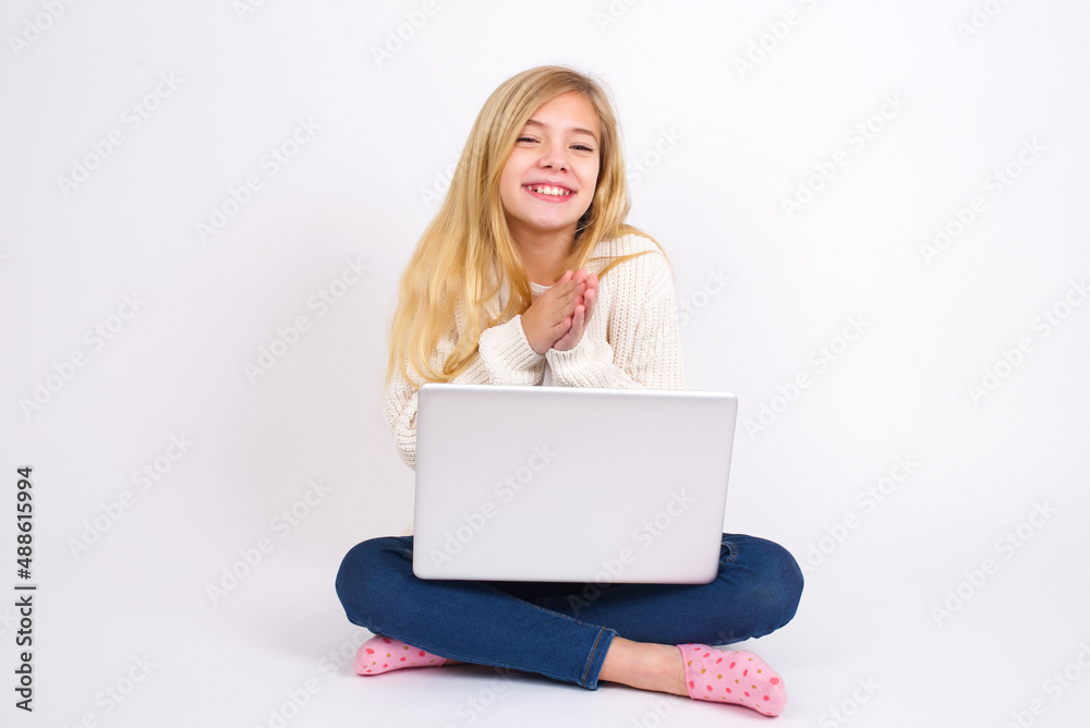 caucasian teen girl sitting with laptop in lotus position on white background , feeling happy, smiling and clapping hands, saying congratulations with an applause. caucasian teen girl sitting with laptop in lotus position on white background , feeling happy, smiling and clapping hands, saying congratulations with an applause.