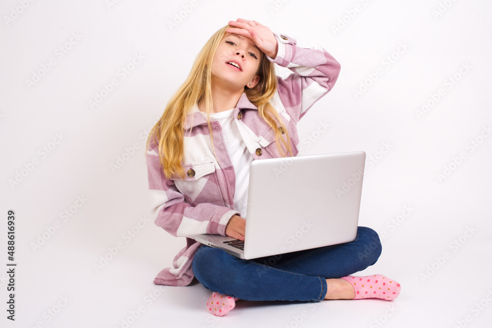 caucasian teen girl sitting with laptop in lotus position on white wiping forehead with hand making phew gesture, expressing relief feels happy that he prevented huge disaster. It was close enough caucasian teen girl sitting with laptop in lotus position on white wiping forehead with hand making phew gesture, expressing relief feels happy that he prevented huge disaster. It was close enough