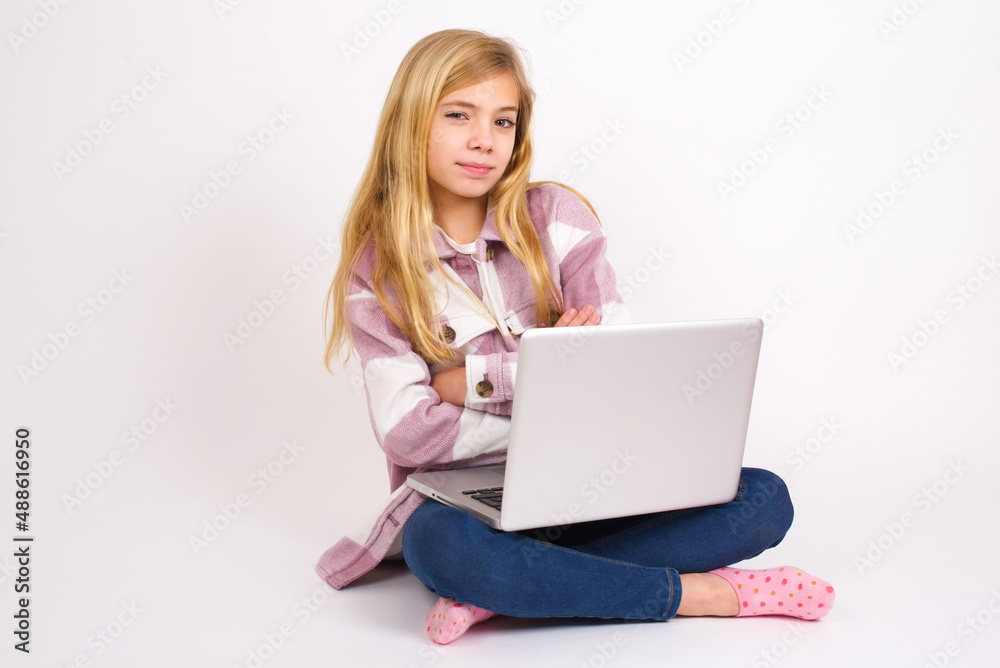 Waist up shot of self confident caucasian teen girl sitting with laptop in lotus position on white background has broad smile, crosses arms, happy to meet with colleagues. Waist up shot of self confident caucasian teen girl sitting with laptop in lotus position on white background has broad smile, crosses arms, happy to meet with colleagues.