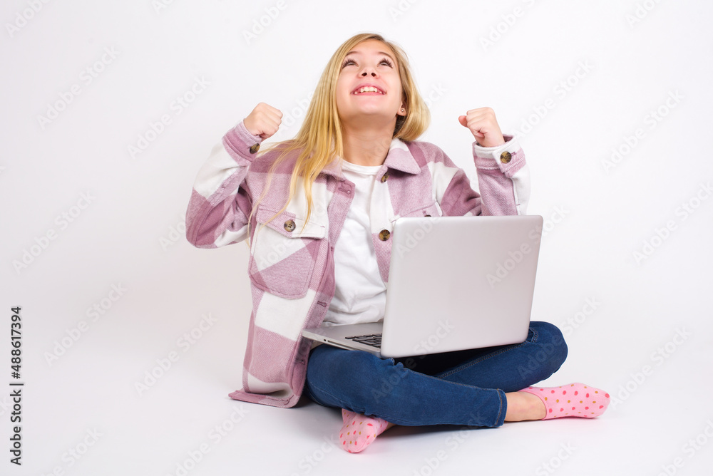 caucasian teen girl sitting with laptop in lotus position on white background champion having success being glad to achieve his goals. Victory and triumph concept. caucasian teen girl sitting with laptop in lotus position on white background champion having success being glad to achieve his goals. Victory and triumph concept.