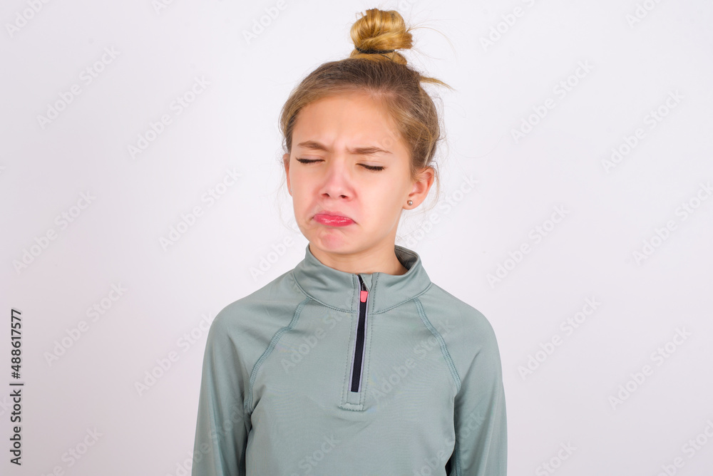 Dismal gloomy rejected little caucasian kid girl with hair bun wearing ...