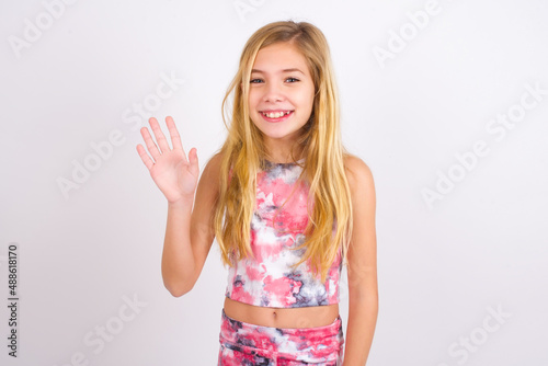 little caucasian kid girl wearing sport clothing over white background shows middle finger bad sign asks not to bother. Provocation and rude attitude.