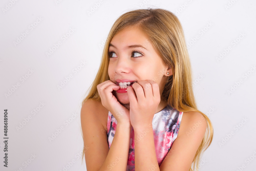 Terrified little caucasian kid girl wearing sport clothing over white background looks empty space home alone moonless night Terrified little caucasian kid girl wearing sport clothing over white background looks empty space home alone moonless night