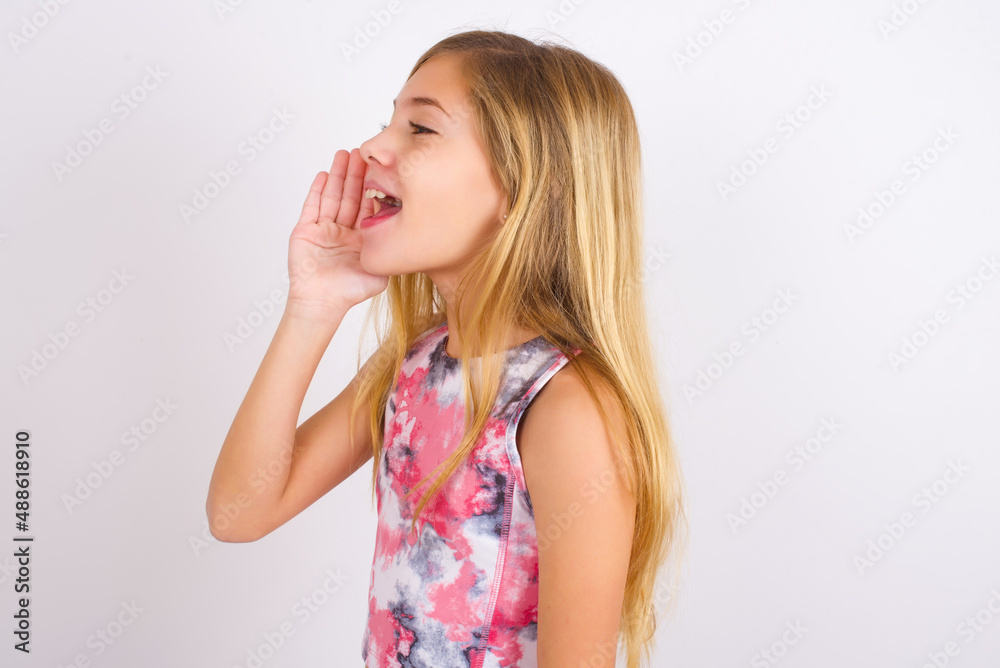 little caucasian kid girl wearing sport clothing over white background look empty space holding hand near her face and screaming or calling someone. little caucasian kid girl wearing sport clothing over white background look empty space holding hand near her face and screaming or calling someone.