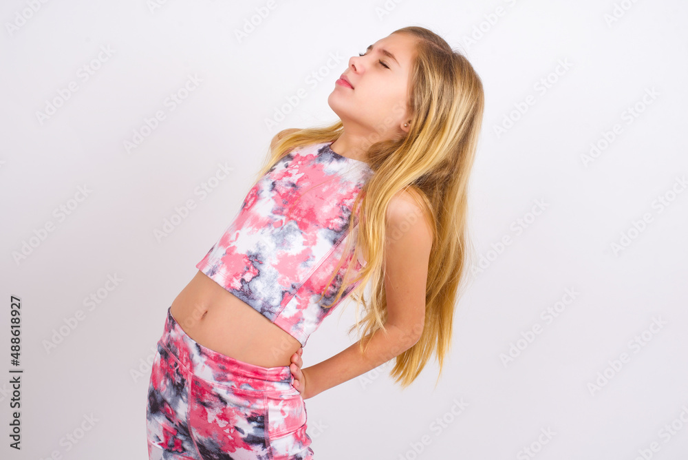 little caucasian kid girl wearing sport clothing over white background got  back pain Stock Photo