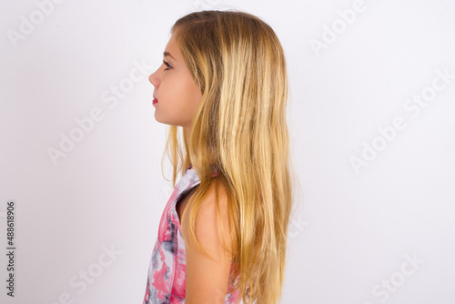 Profile portrait of nice little caucasian kid girl wearing sport clothing over white background look empty space toothy smile