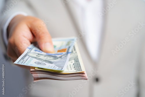 Focus select and blur Foreground Business man and money in us dollar hold on hand wearing a brown suit jacket and Give to me USD, Pay, exchange money vietnamese on white background.