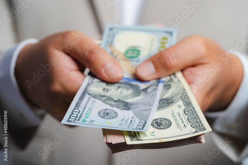 Business man and money in us dollar hold on hand wearing a brown suit jacket and Give to me USD, Pay, exchange money vietnamese on white background.