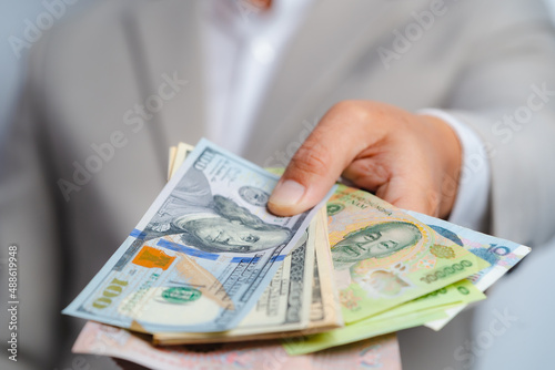 Business man and money in us dollar and Vietnam Dong, VND hold on hand wearing a brown suit jacket and Give to me USD, Pay, exchange money vietnamese on white background.