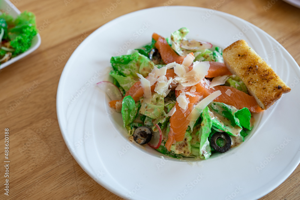 fresh Salmon salad with fresh green leaves and black olive on white plate. fresh Salmon salad with fresh green leaves and black olive on white plate.