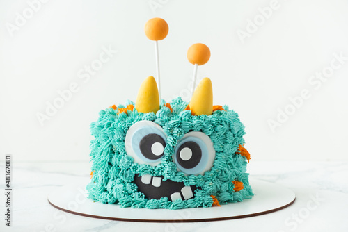 Monster theme cake on the white background. Birthday cake with turquoise fluffy cream cheese frosting